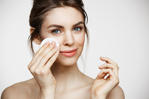 PEELING-500X333cute-beautiful-natural-brunette-girl-cleaning-face-with-cotton-sponge-smiling-looking-camera-white-background-cosmetology-spa